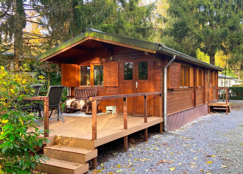 a wooden cabin with a deck and a dog at Rust en Natuur in Ons Vrijstaande Fins Chalet in Epe