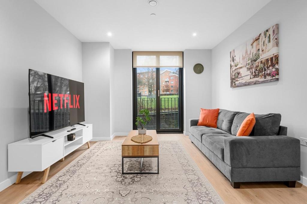 a living room with a gray couch and a tv at Manchester Haven Luxury Apartment in Manchester
