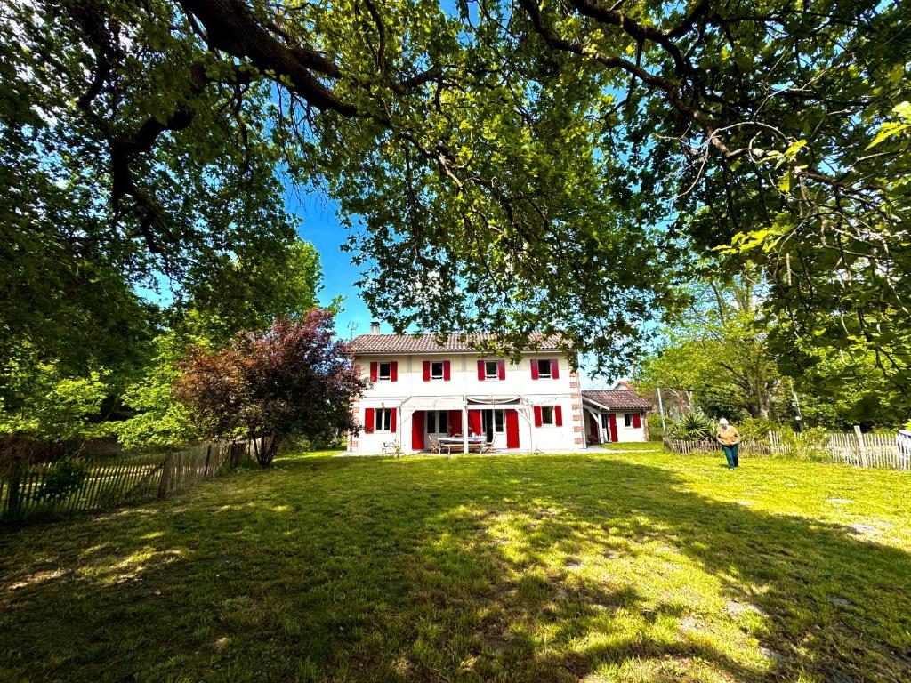 un homme debout devant une maison blanche dans l'établissement Grande maison entre Lac et forêt, à Gastes