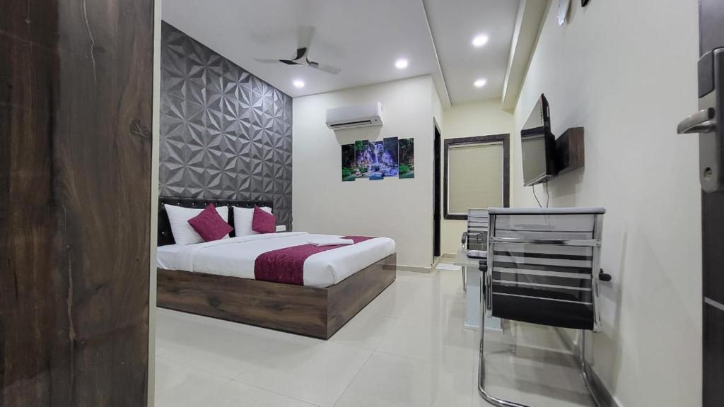 a bedroom with a bed with pink pillows and a tv at Hotel Vaishnavi Grand in Miriālgūda