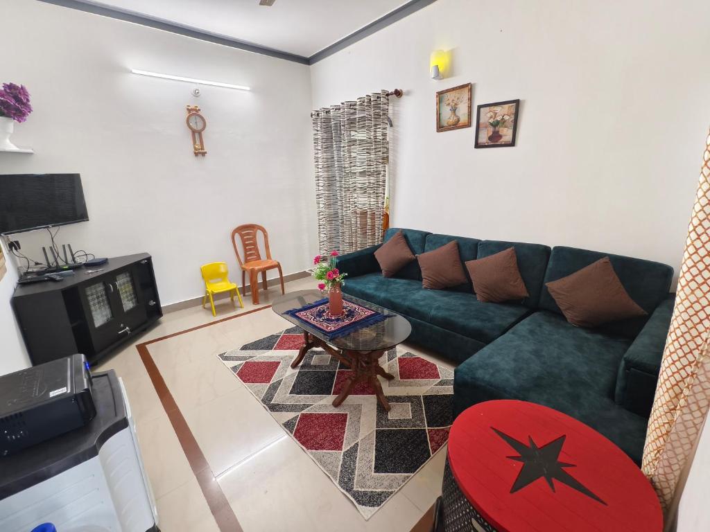 a living room with a green couch and a table at ZTRIO Vacations in Chikmagalūr