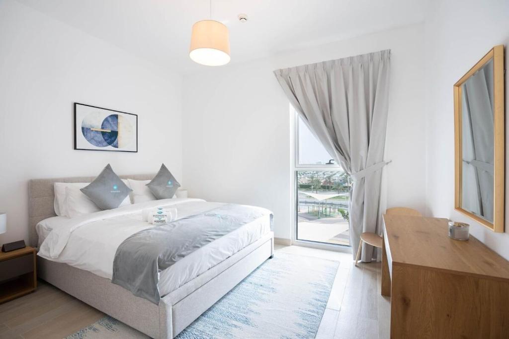 ein weißes Schlafzimmer mit einem Bett und einem großen Fenster in der Unterkunft Bloomfields Iconic 1br Waters Edge Yas Island in Abu Dhabi