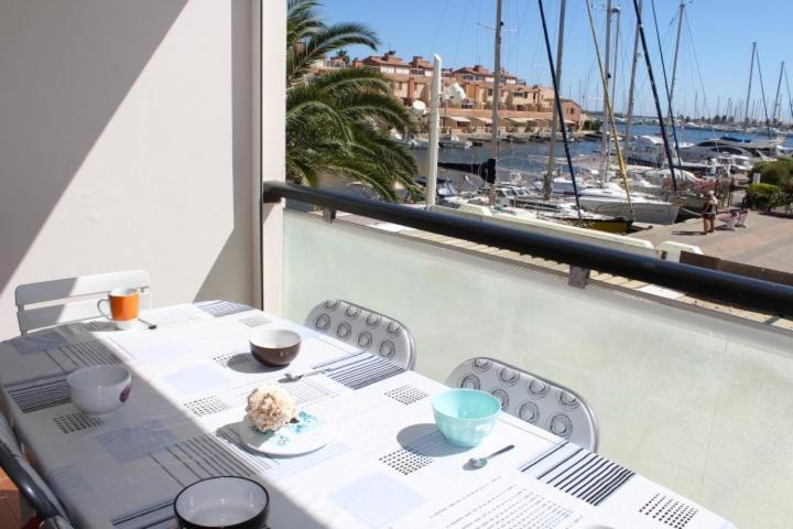 une table sur un balcon avec vue sur un port dans l'établissement Appartement 2 pièces cabine - GRUISSAN GN400-013, à Gruissan