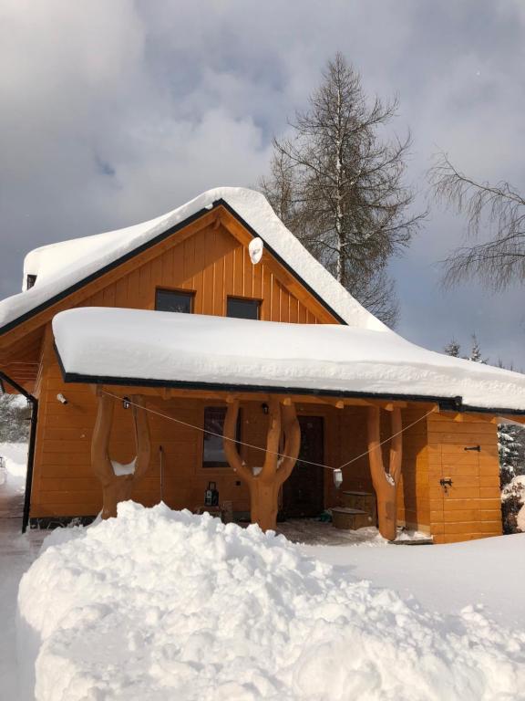 une cabane en bois avec de la neige sur le toit dans l'établissement Chata pri potoku, à Hruštín