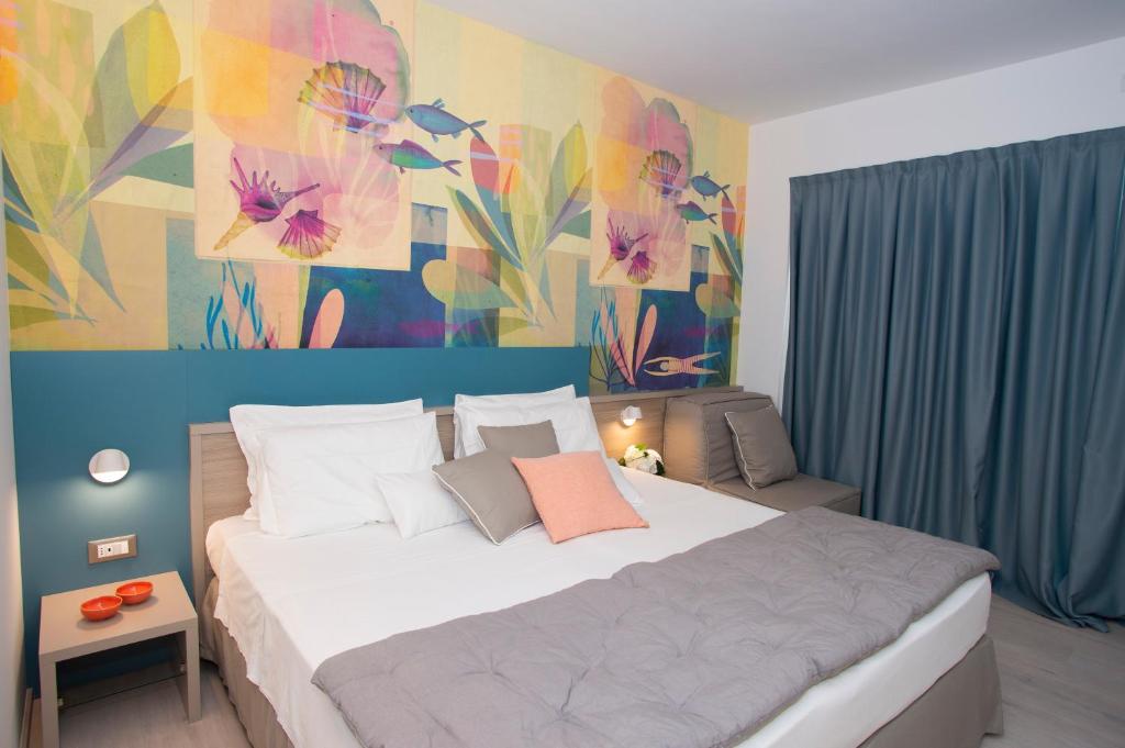 a bedroom with a large bed with a painting on the wall at Hotel President in Lignano Sabbiadoro