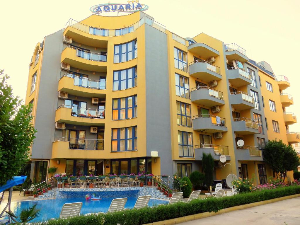 a hotel with a swimming pool in front of a building at Aquaria Holiday Apartments in Sunny Beach