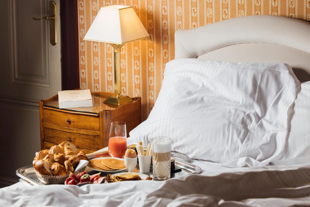 a tray of food on a bed with a breakfast at Le Castel Marie Louise in La Baule