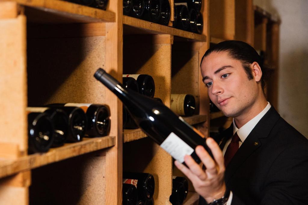 a man in a suit pouring a bottle of wine at Le Castel Marie Louise in La Baule