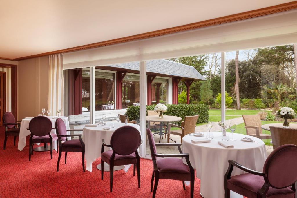 a dining room with white tables and chairs at Le Castel Marie Louise in La Baule