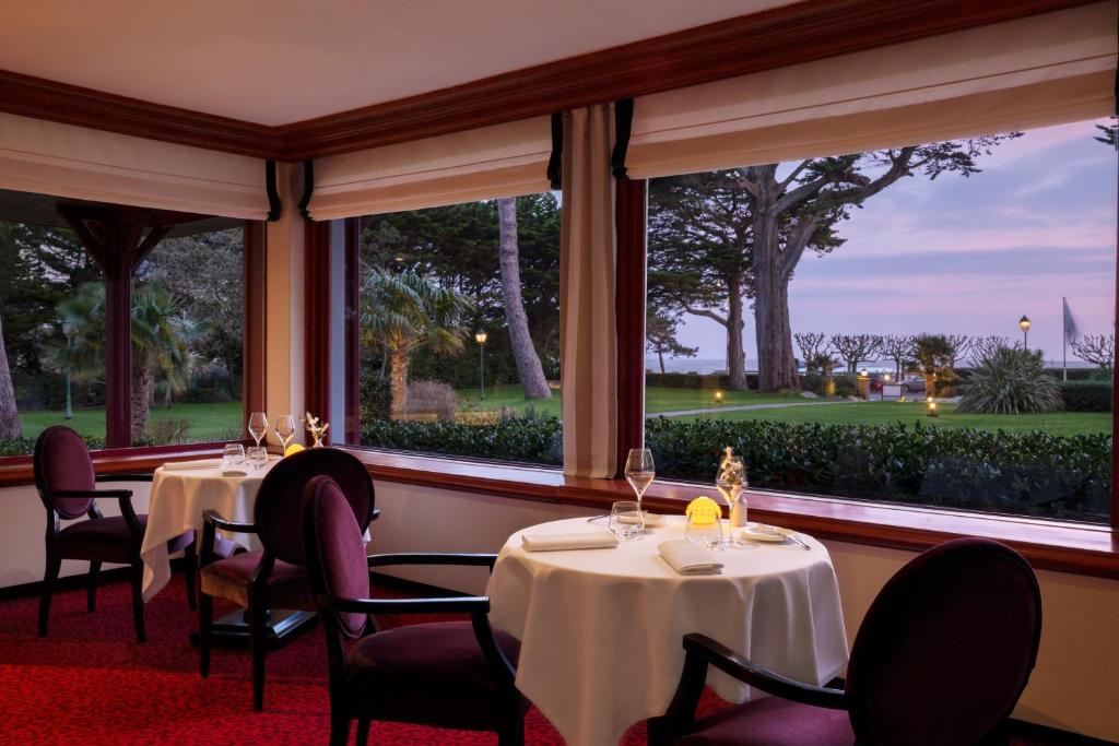 a dining room with tables and chairs and windows at Le Castel Marie Louise in La Baule