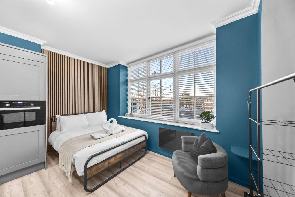 a bedroom with blue walls and a bed and a chair at Downtown Studio 1 - Harrogate Town Centre in Harrogate