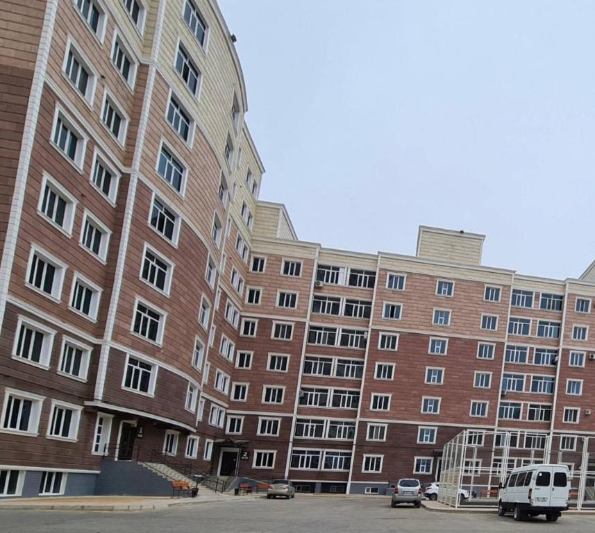 a large brick building with a van parked in front of it at Apartments comfort new, Aktau 16 77 in Aktau