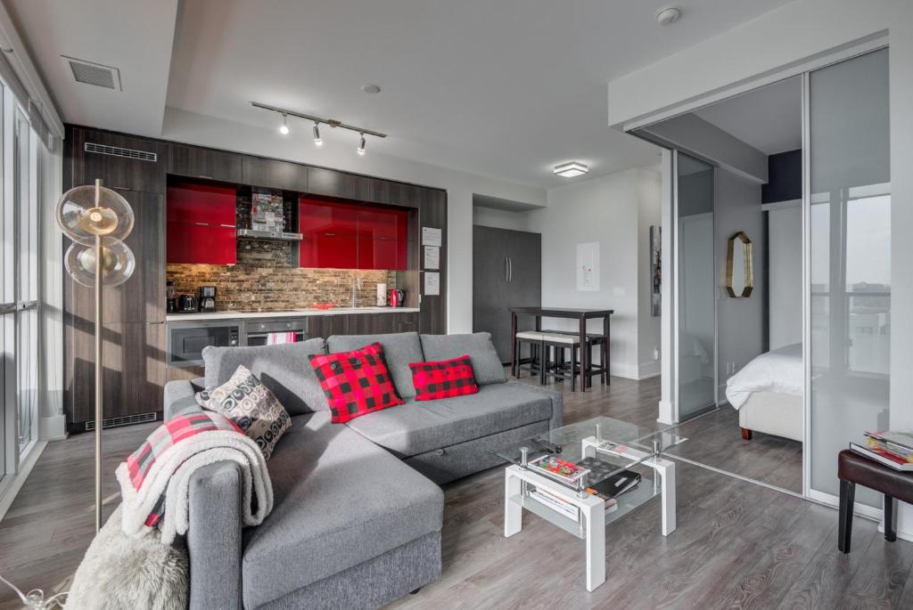 ein Wohnzimmer mit grauem Sofa und roten Kissen in der Unterkunft CN lovers in Toronto