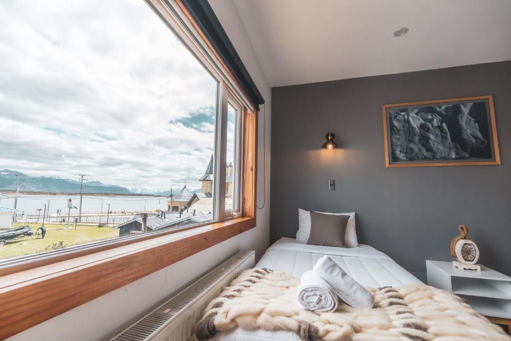 a bed in a room with a large window at Pristine Patagonia Hotel in Puerto Natales