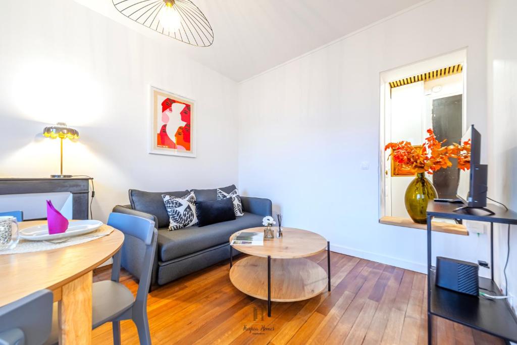 een woonkamer met een bank en een tafel bij L'Escale Parisienne Charmant T2 proche métro et Paris in Pantin