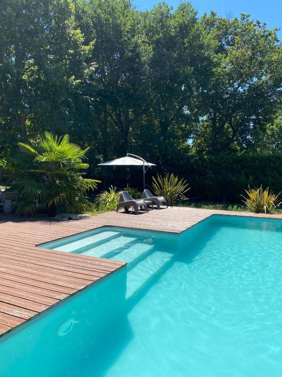 - une piscine bleue avec des chaises et un parasol dans l'établissement Villa avec piscine, à Martignas-sur-Jalle