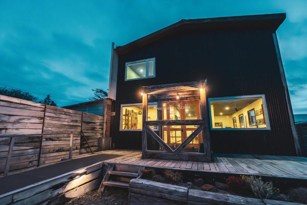 a black house with a wooden door on a deck at Pristine Patagonia Hotel in Puerto Natales