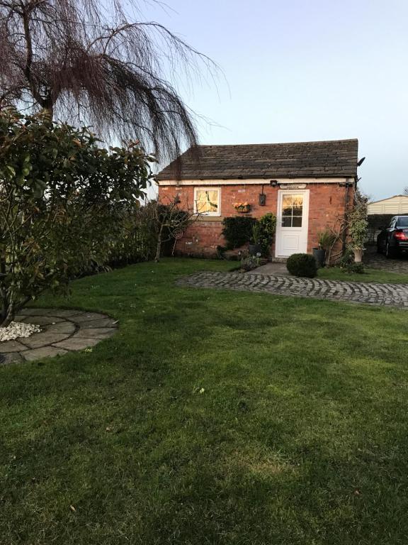une petite maison en brique avec une pelouse dans l'établissement Sefton Cottage, à Ormskirk