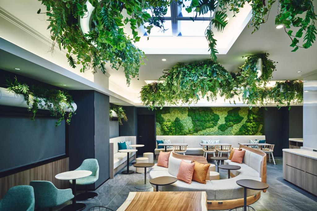un hall d'entrée avec des tables, des chaises et des plantes dans l'établissement Garner Hotel Osaka Honmachi Kita Semba by IHG, à Osaka