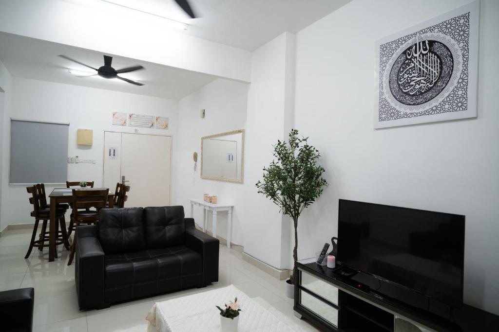 a living room with a black couch and a flat screen tv at Melati Homestay in Kuala Terengganu