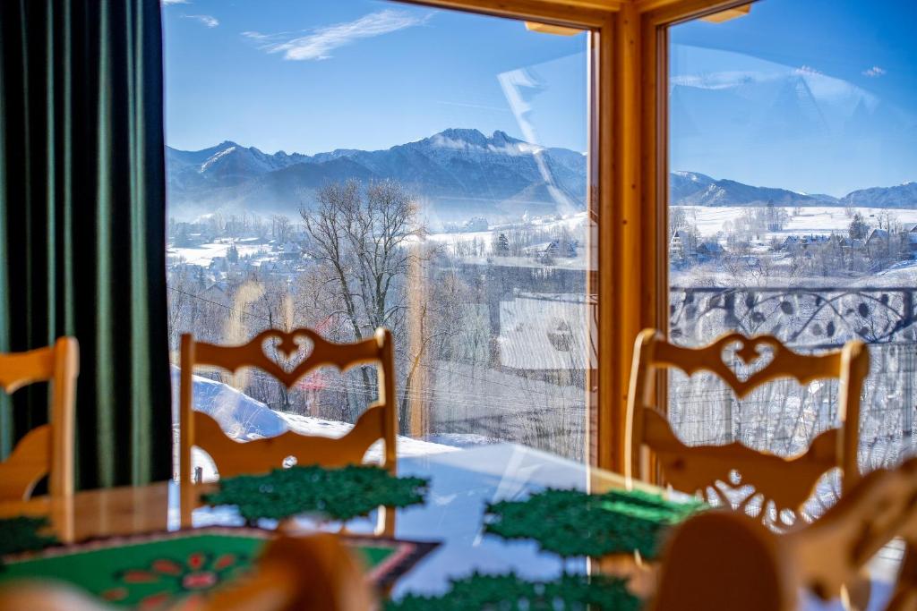 een eetkamer met een tafel en stoelen voor een raam bij Topory Prestige House sauna & jacuzzi in Zakopane