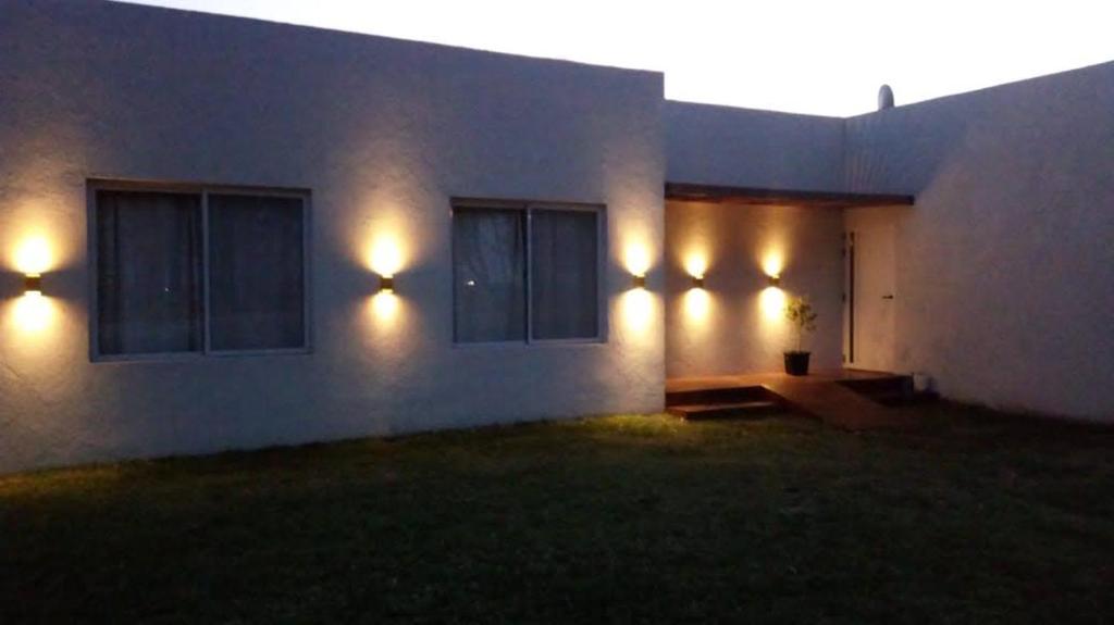 a house with lights on the side of it at night at Complejos EG in San Miguel del Monte