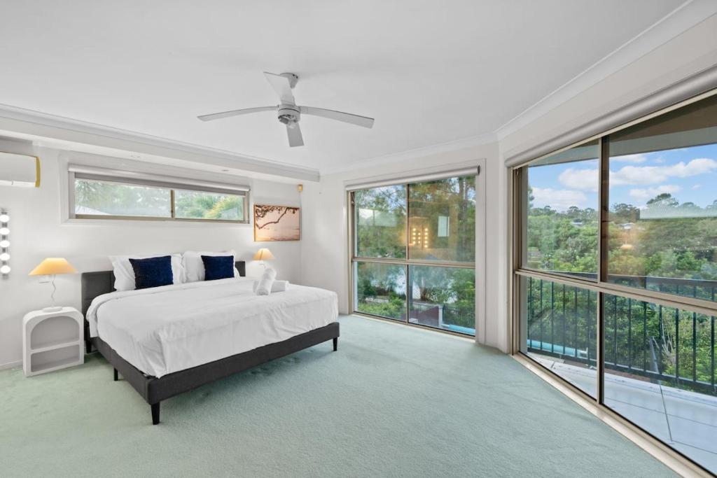 a bedroom with a bed and large windows at Front Lake View 4Bed Home with Pool and Mins to Mall in Doolandella