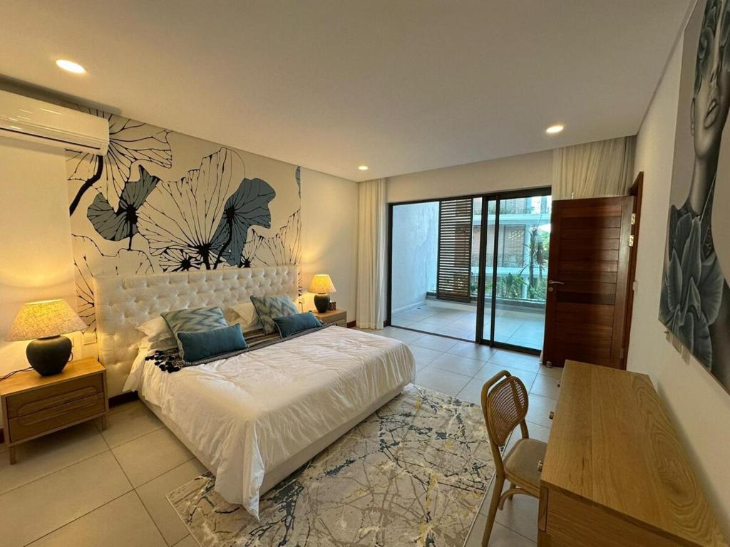a bedroom with a large bed and a table and a desk at Joyau de pointe aux Canonniers in Grand Baie
