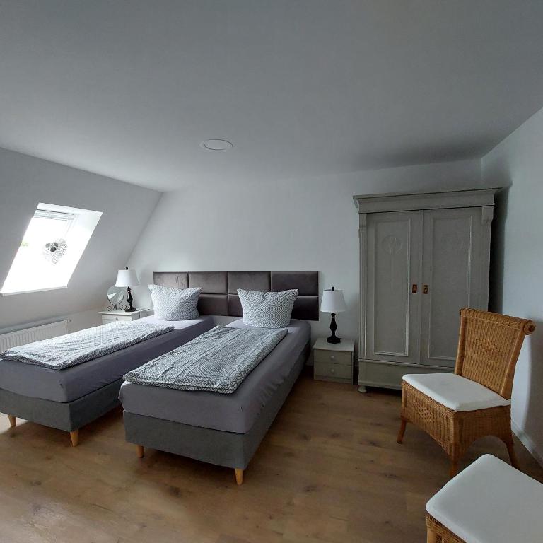 a bedroom with two beds and a chair and a window at FeWo Dreiseitenblick Komfort mit 2 Schlafzimmern in Bad Doberan