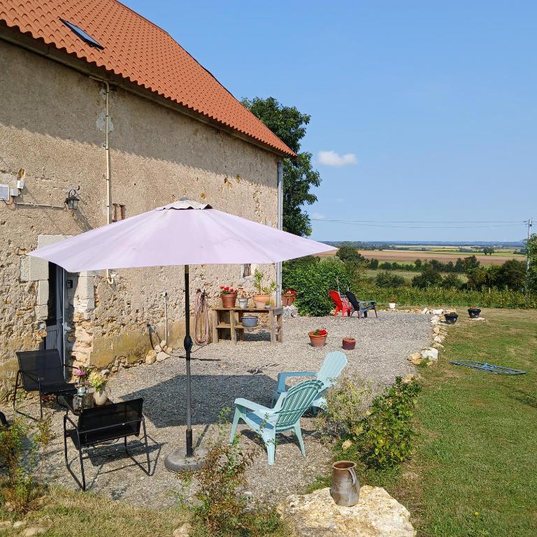un parasol, deux chaises et une table dans la cour dans l'établissement Domaine Lavau - Gîte L'Artisane, à Néret