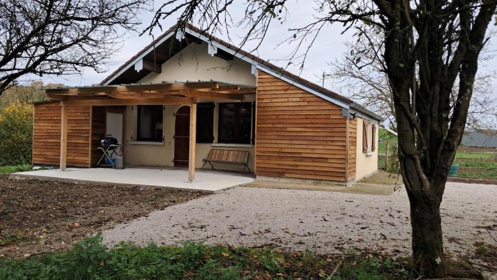 une petite maison en bois avec un arbre devant dans l'établissement Chez Marcel, à Échenans
