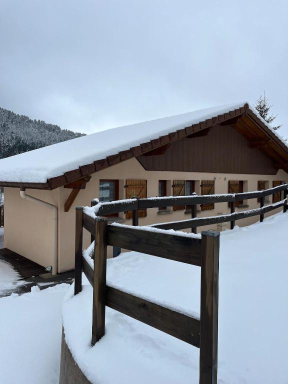 une maison recouverte de neige avec une clôture dans l'établissement Gîte La Bresse 7 personnes, à La Bresse