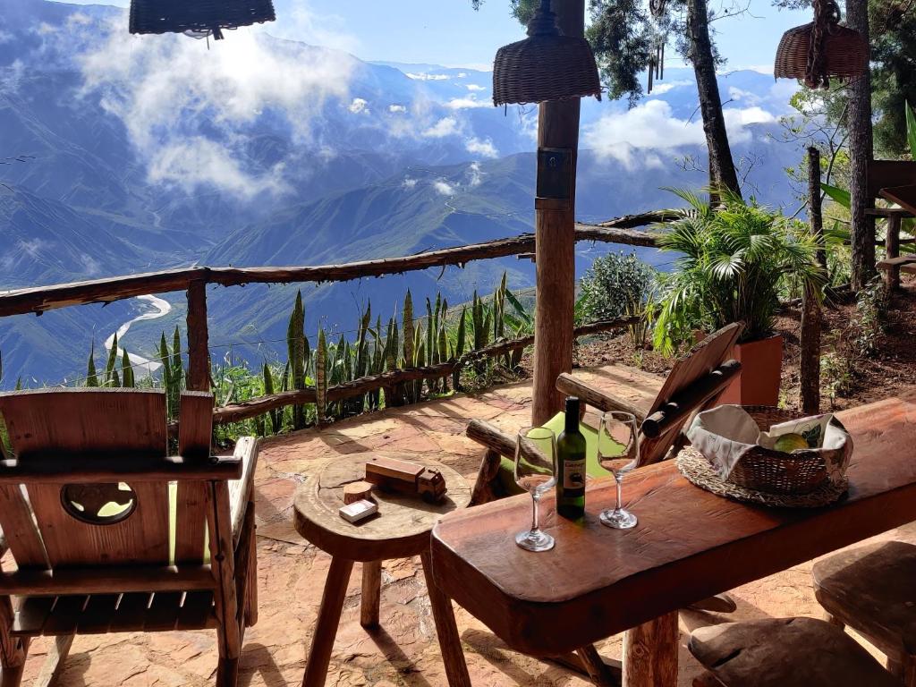 a table with wine glasses and a view of a mountain at Chalet Mirador Chicamocha in Los Santos