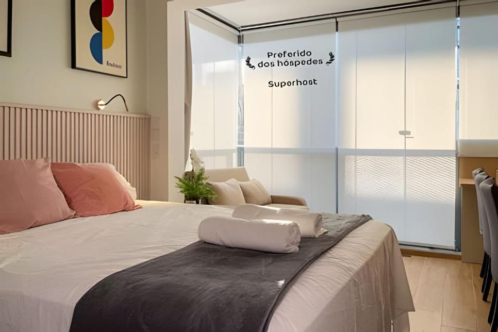 um quarto com uma cama grande com lençóis brancos em Luxo Novo e Aconchegante entre Pinheiros e Jardins em São Paulo