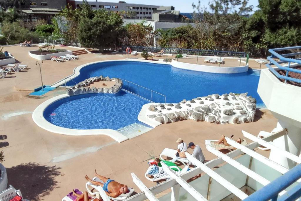 a large swimming pool with people sitting in chairs around it at Welcoming studio in Santa Cruz, 33 m², shared pool in Callao Salvaje