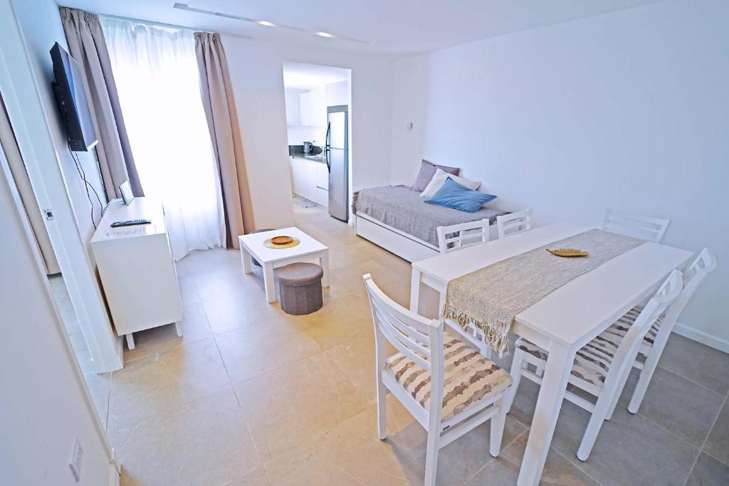 - un salon avec une table et des chaises blanches ainsi qu'un lit dans l'établissement NOR 404 - Departamento de categoría con hermosas vistas, à Ushuaia