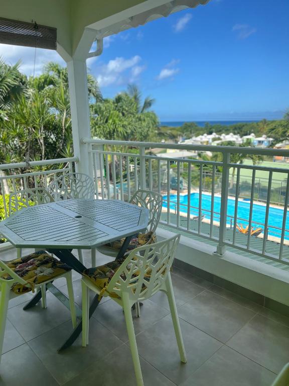 a table and chairs on a balcony with a pool at Les Algues de la Chapelle in Anse-Bertrand
