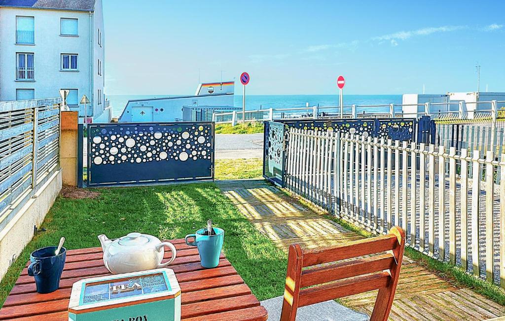 a wooden table with a bench and a fence at 2 Bedroom Cozy Home In Jullouville in Jullouville-les-Pins