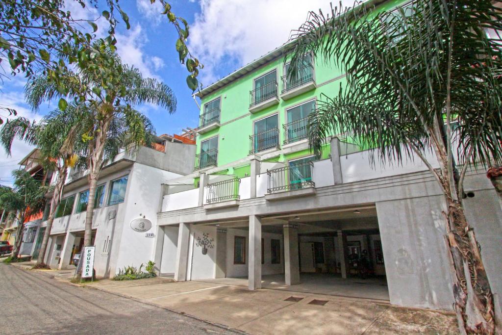 a green and white building with palm trees in front of it at Aventureiro Pousada in Teresópolis