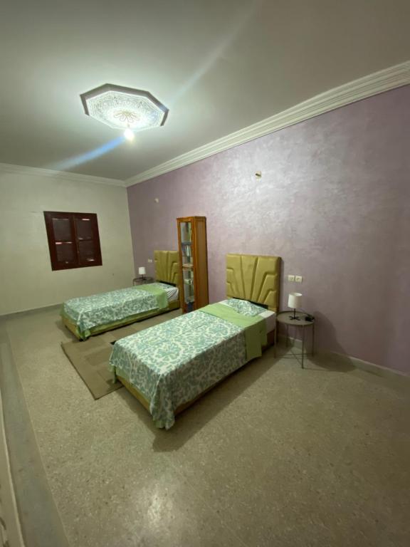 a room with two beds and a table and chairs at Bel appartement familial au centre ville in El Kelaa des Srarhna