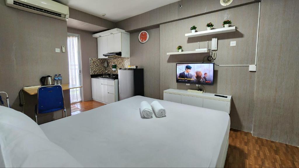 a kitchen with a white bed and a tv on a wall at BassuraCity Apartment near Hi-Speed Train Station -Min Stay 3 nights- in Jakarta