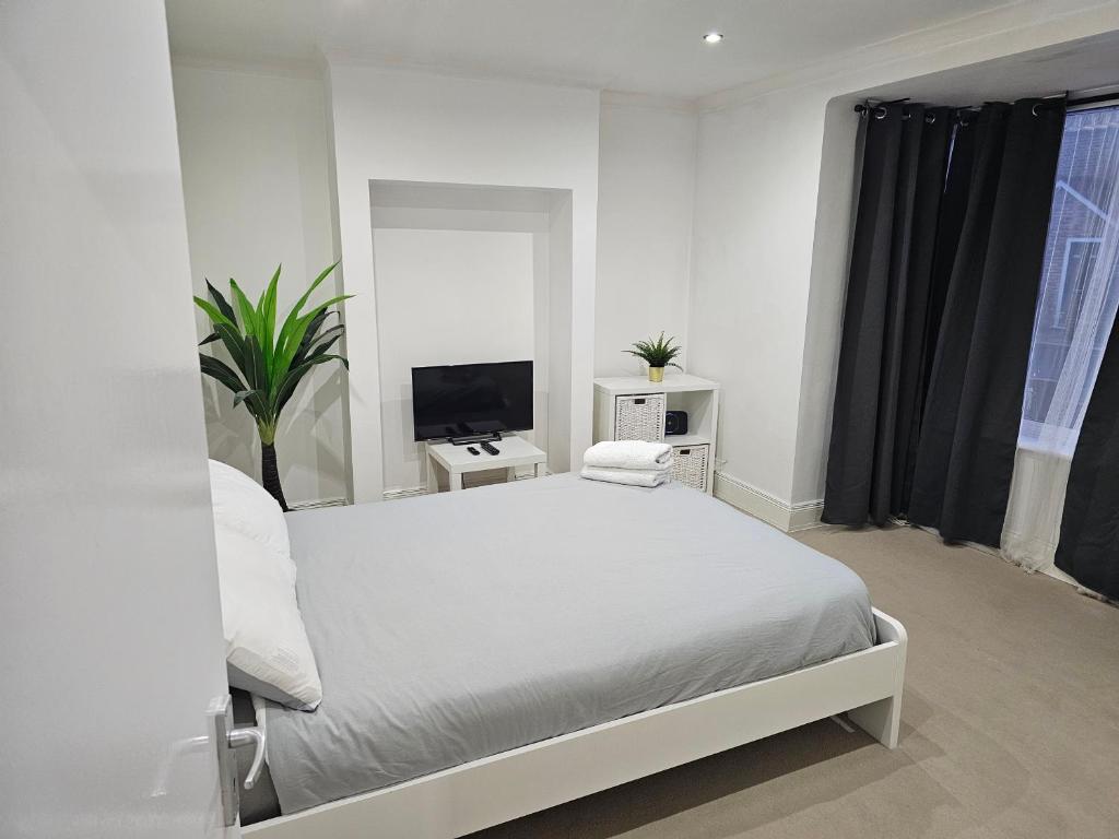 a white bedroom with a bed and a tv at Mirandas Place in Gillingham