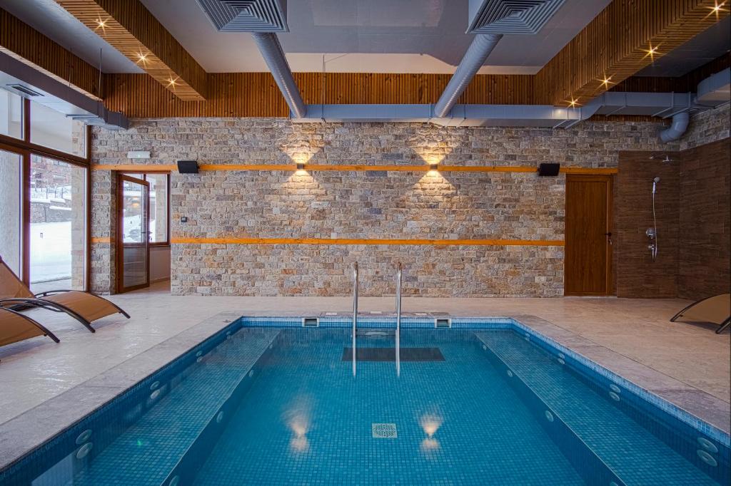 a swimming pool in a room with a brick wall at SPA Hotel Daffi in Smolyan
