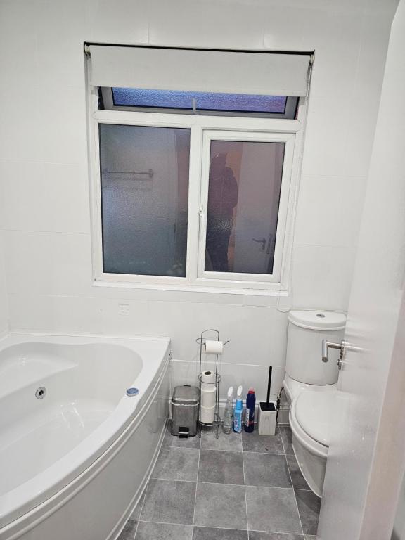 a bathroom with a tub and a toilet and a window at Mirandas Place in Gillingham