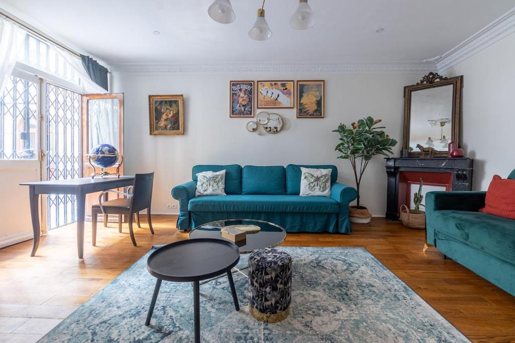 un salon avec un canapé bleu et une table dans l'établissement Appartement 2 étages Paris - Métro 9 Grands Boulevards - Folies Bergères, à Paris
