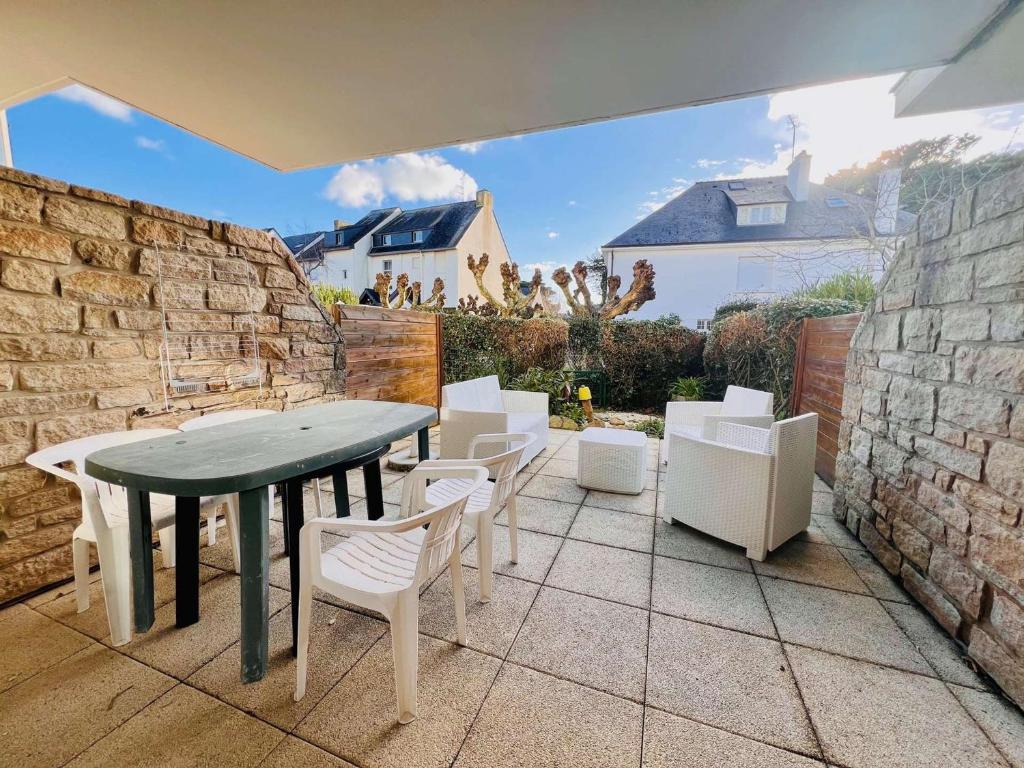 un patio avec une table et des chaises et un mur en pierre dans l'établissement Appartement 2 pièces avec jardin et parking, proche plage et commerces à Quiberon - FR-1-478-306, à Quiberon