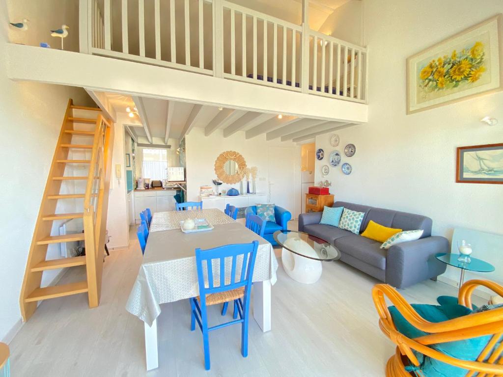 un salon avec une table et des chaises bleues dans l'établissement Appartement 4/5 pers, piscine, face mer, Fouras - FR-1-709-82, à Fouras