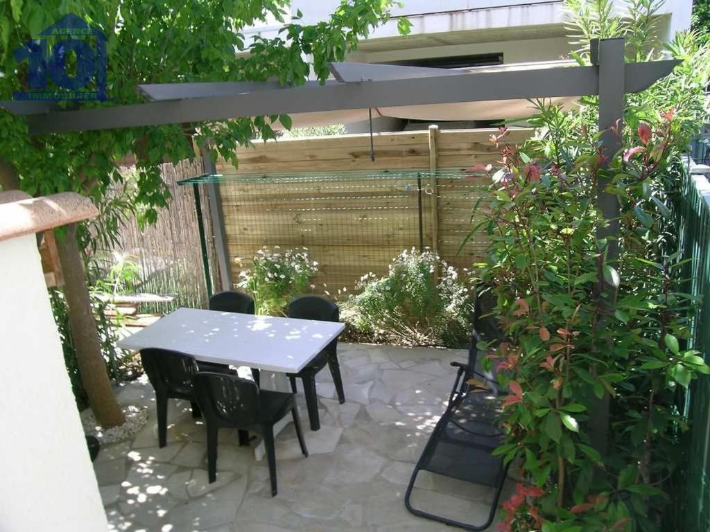 un patio avec une table et des chaises sous une pergola dans l'établissement Pavillon 300m Plage avec Piscine et Parking, Climatisation - FR-1-781-79, à Valras-Plage