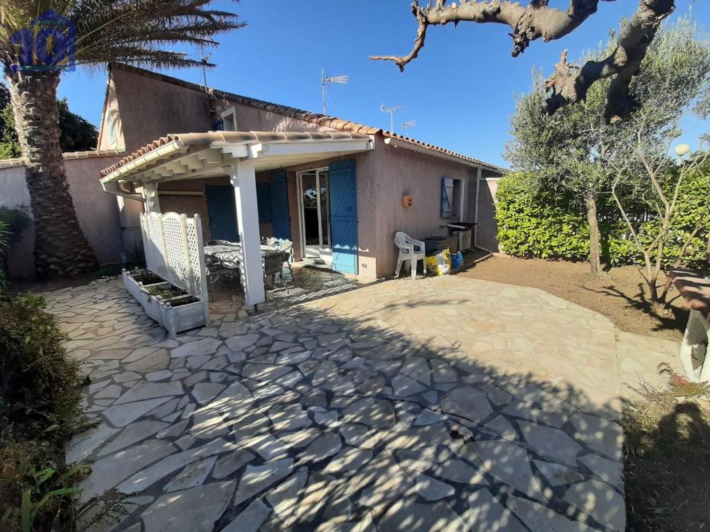 une maison avec une terrasse en face de celle-ci dans l'établissement Pavillon 6 pers clim, piscine, parking privé, proche plage - FR-1-781-80, à Vendres
