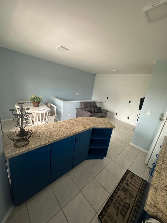 a kitchen with blue cabinets and a living room at Apartamento 4 quadras do mar! in Xangri-lá